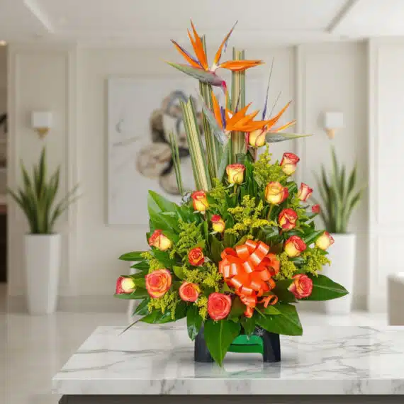 Arreglo floral exótico Esplendor con aves del paraíso y rosas, sobre mesa de mármmol en un elegante lobby de hotel boutique.