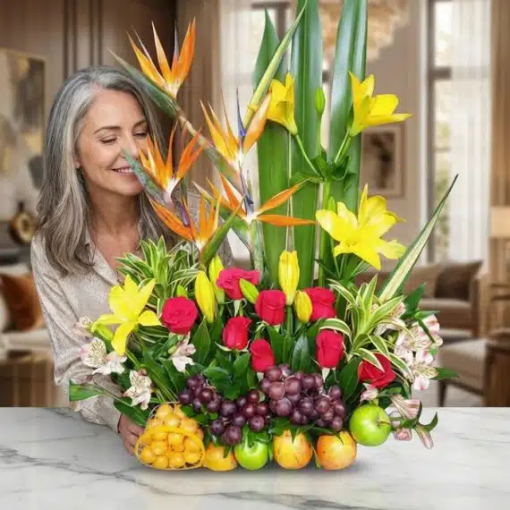 Mujer elegante de cabello gris admirando con deleite un Arreglo Floral con Frutas Akebia, compuesto por aves del paraíso, lir