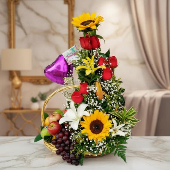 Arreglo Floral con Frutas Capella: Elegancia y Frescura para Regalar Arreglo floral Capella con girasoles, rosas rojas, lirios blancos y amarillos, y follaje verde, acompañado de una cesta con u