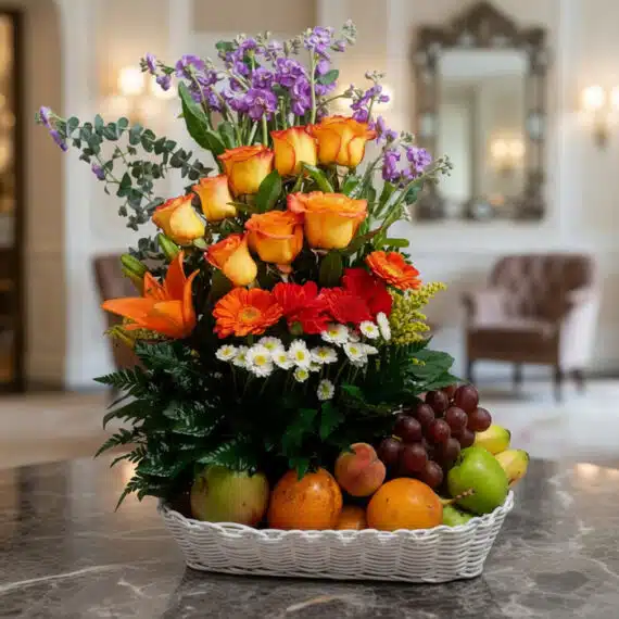 Arreglo Floral con Frutas Hadar: Frescura y Elegancia para Regalar Arreglo floral Hadar con rosas naranjas, lirios, gerberas y margaritas, acompañado de frutas frescas como uvas, manzanas, nar