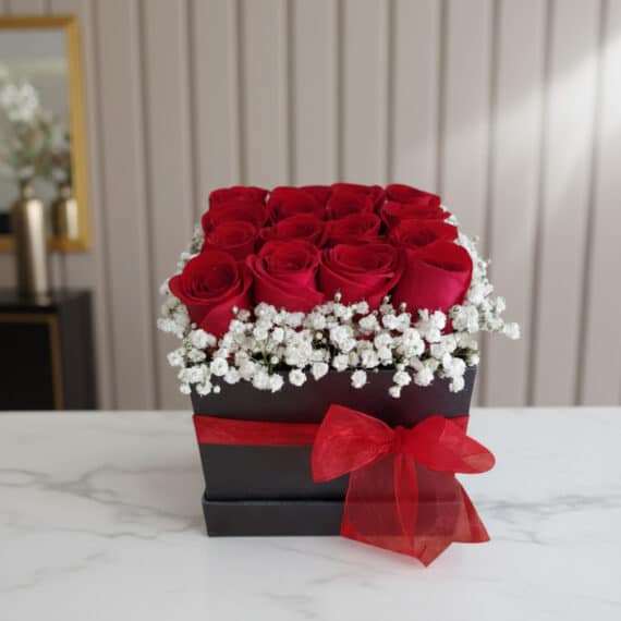 Arreglo Floral Pétalos: Rosas Rojas Frescas en Caja Elegante Arreglo floral Pétalos con rosas rojas frescas y gypsophila en una caja negra con lazo rojo, sobre mármol blanco en un entorn