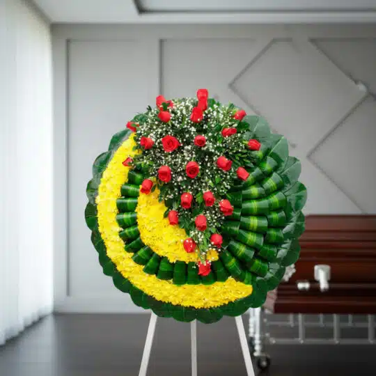 Corona fúnebre Adela con rosas rojas y flores amarillas, diseño moderno para tanatorio, simbolizando condolencias y respeto.