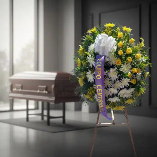 Corona fúnebre 'Estamos Contigo' con flores amarillas y blancas, cinta morada, en sala de velación moderna con ataúd desenfoc