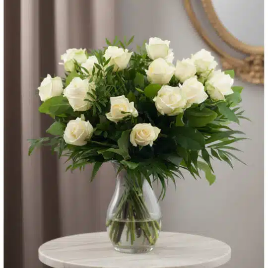 Ramo de 18 rosas blancas frescas en un jarrón de cristal, con follaje verde, sobre una mesa de mármol y fondo elegante.
