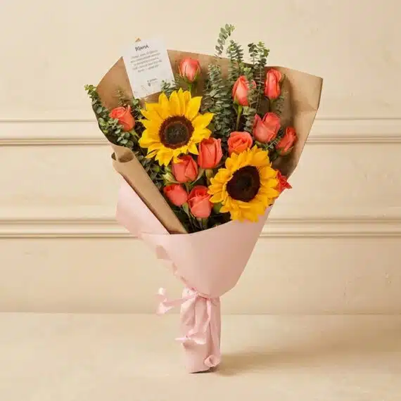 Ramo Beatrice: Rosas Salmón y Girasoles para Expresar Sentimientos Ramo Beatrice con rosas salmón, girasoles vibrantes y eucalipto, envuelto en papel kraft y rosa, ideal para regalar en cualqu
