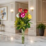 Solitario de rosas multicolor (rojas, blancas, fucsias, amarillas) en un jarrón de cristal, sobre una superficie de mármol, c